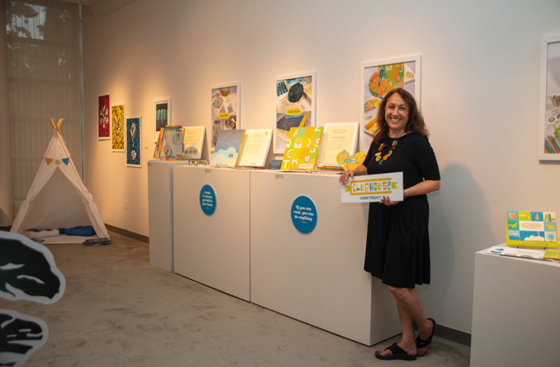 A woman leaning on an art exhibit inside an art gallery.